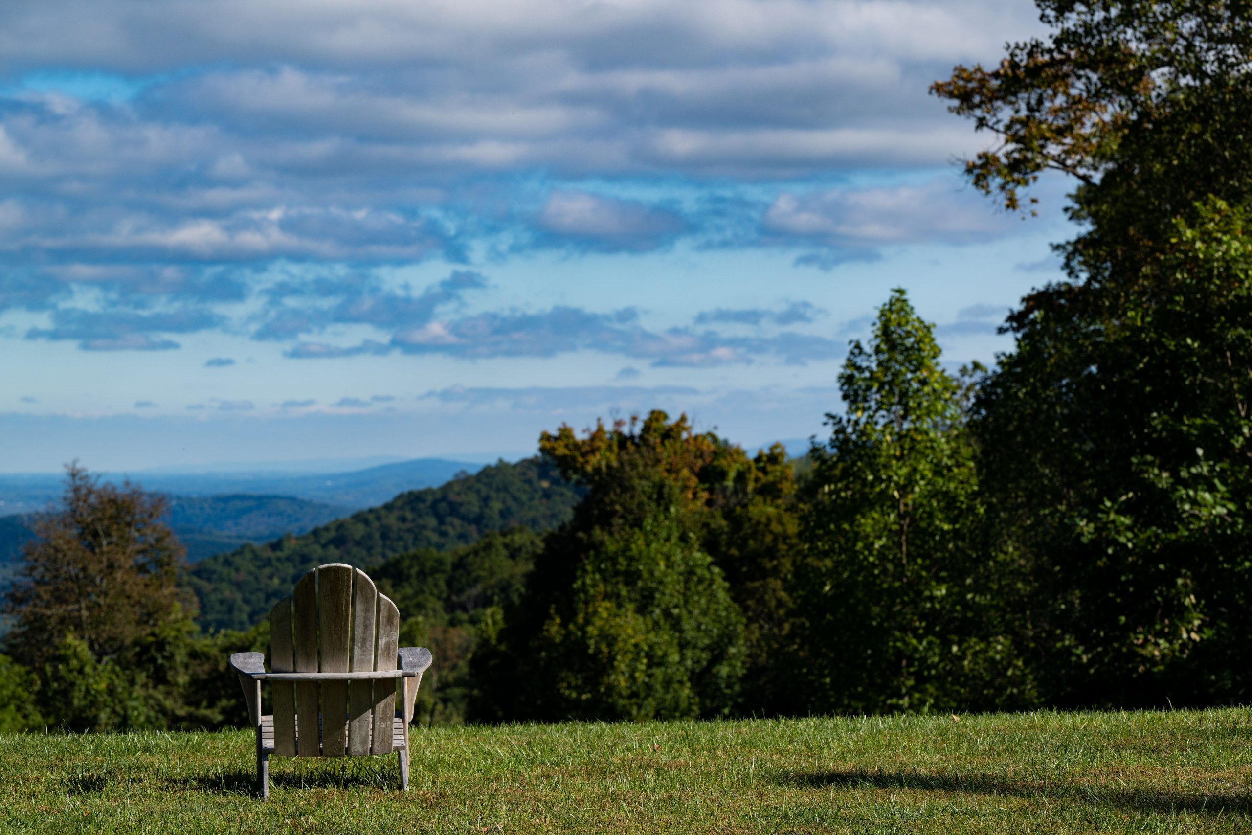A view of a lawn chair facing the mountains and blue skies.