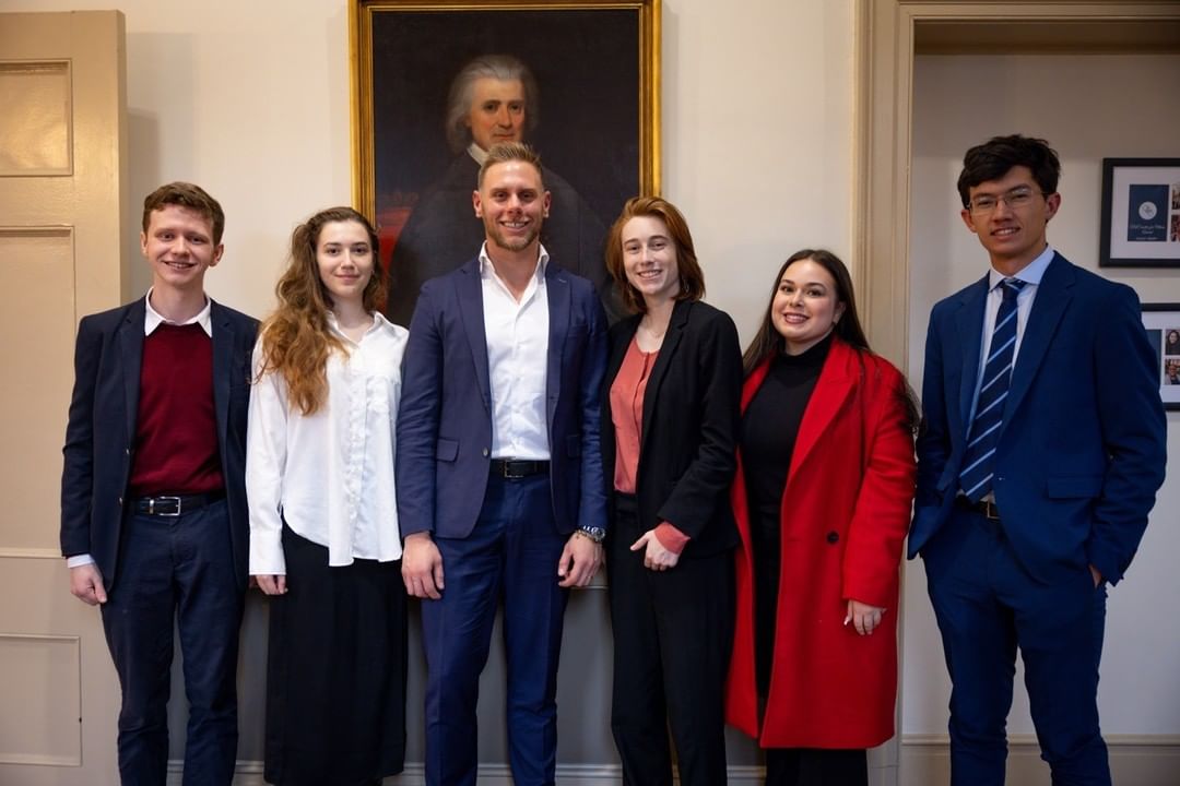 Stepanovych and a group of students standing with Joe Hack in a room.