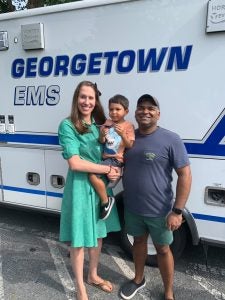 A couple stand with their four-year-old in front of a Georgetown ambulance on campus.