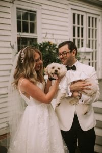 A bride and groom hold a puppy on their wedding day.