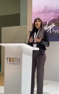 Young woman in business attire speaking behind a podium