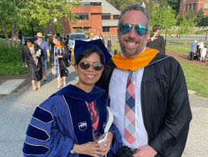 A student and professor in commencement gowns.
