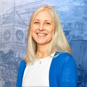 A woman with gray hair smiles in front of a graphic of the clocktower of Georgetown Law.