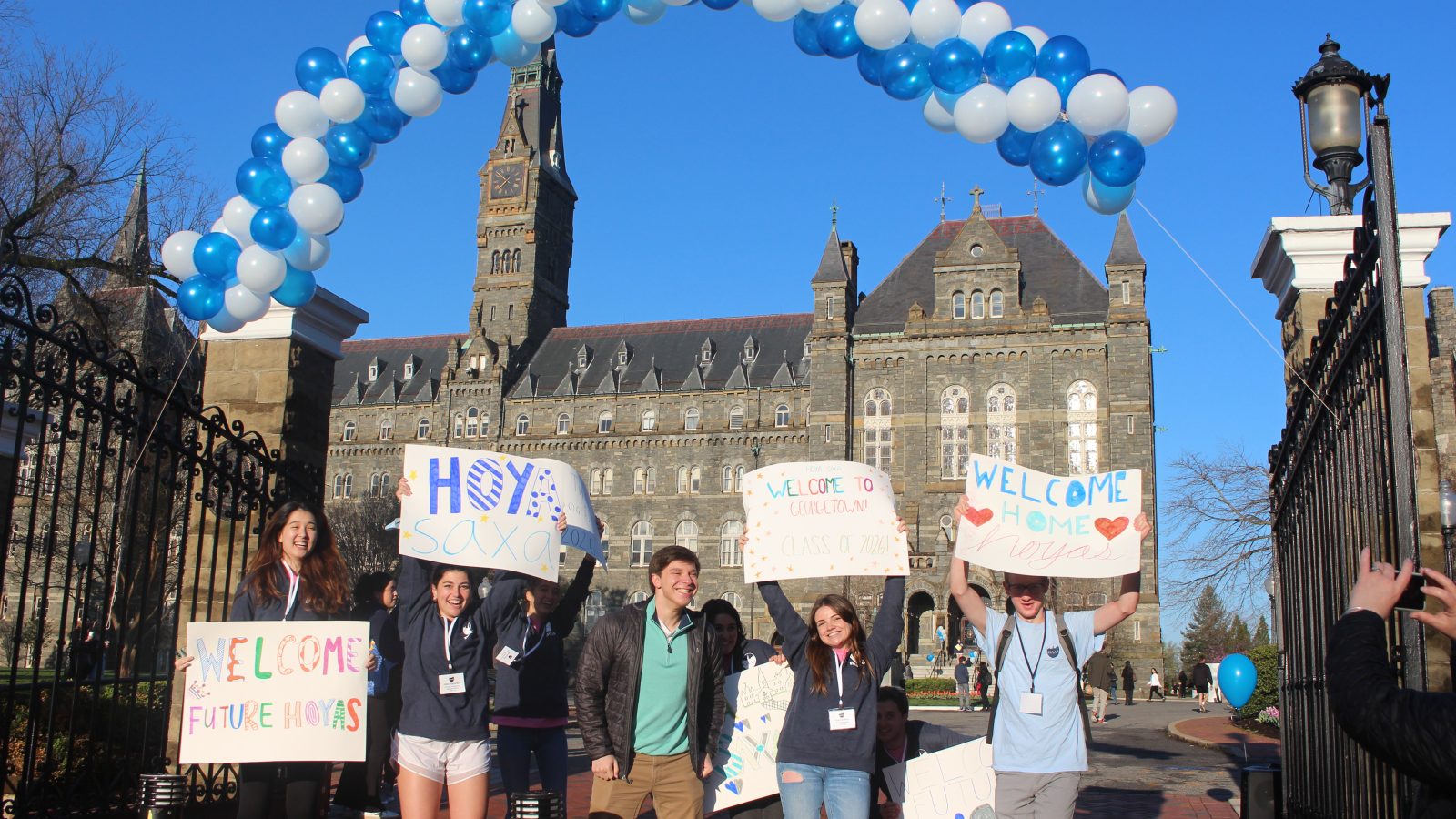 Students in front of Healy Gate with signs welcoming admitted students