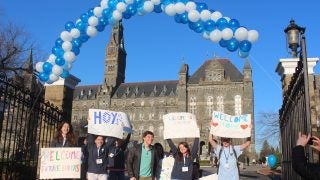 Students in front of Healy Gate with signs welcoming admitted students