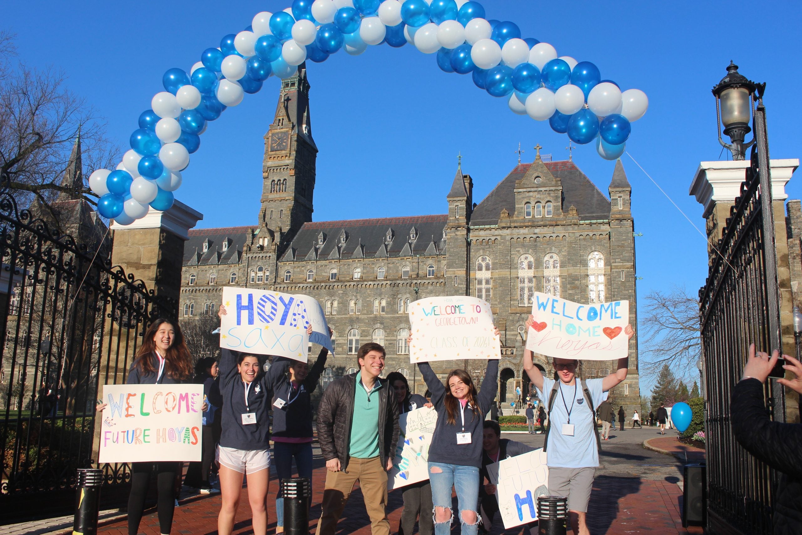 Students in front of Healy Gate with signs welcoming admitted students
