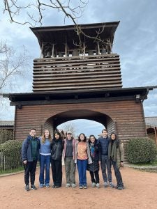 A group of young people standing in front of a bell tower.