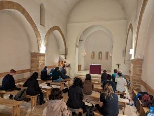 A group of people sitting on benches inside a small church.