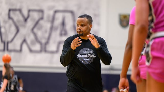 Head Women&#039;s Basketball Coach Darnell Haney walks down the sideline during a game clapping his hands.
