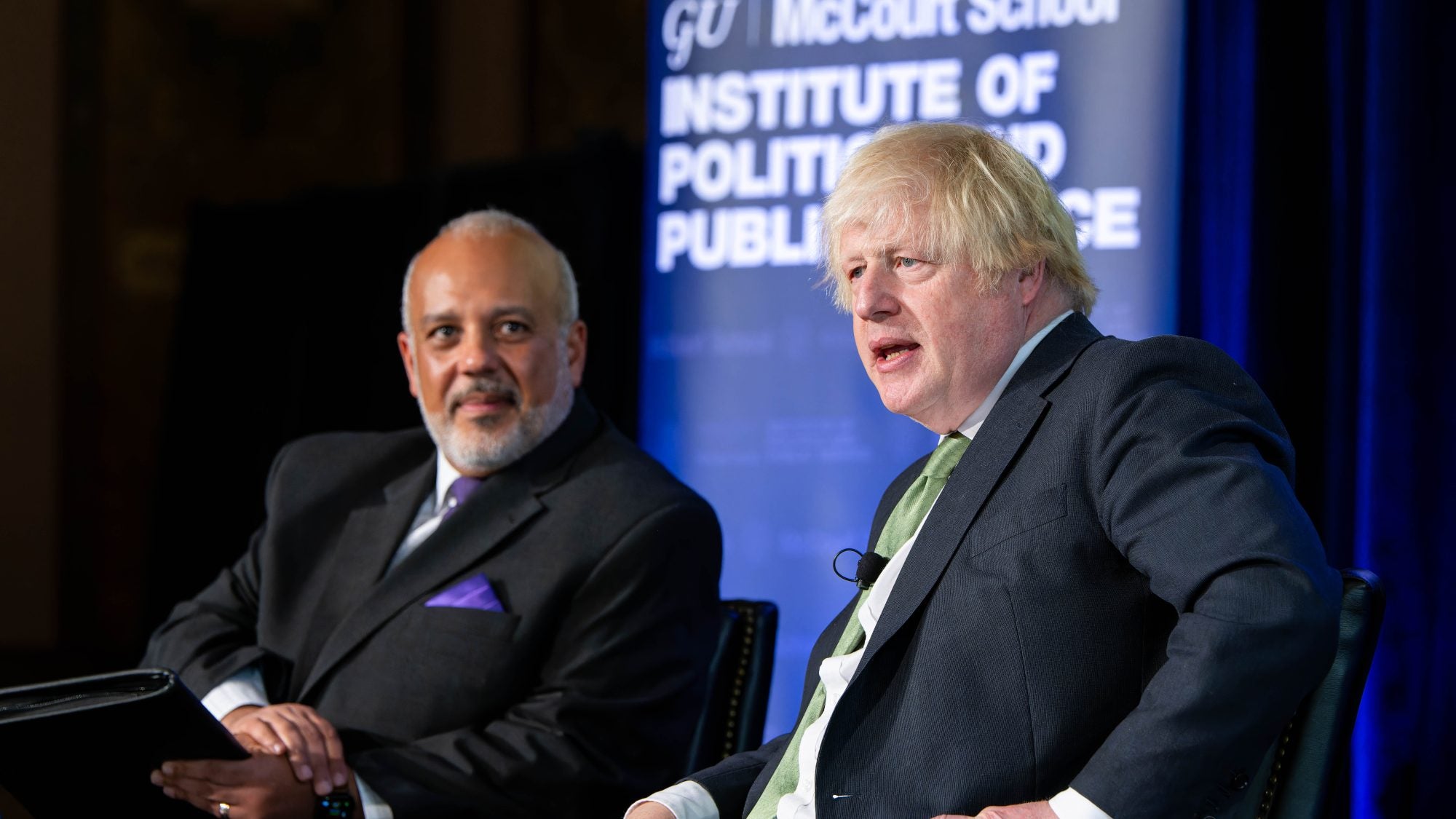 Two men sit on a stage at Georgetown.