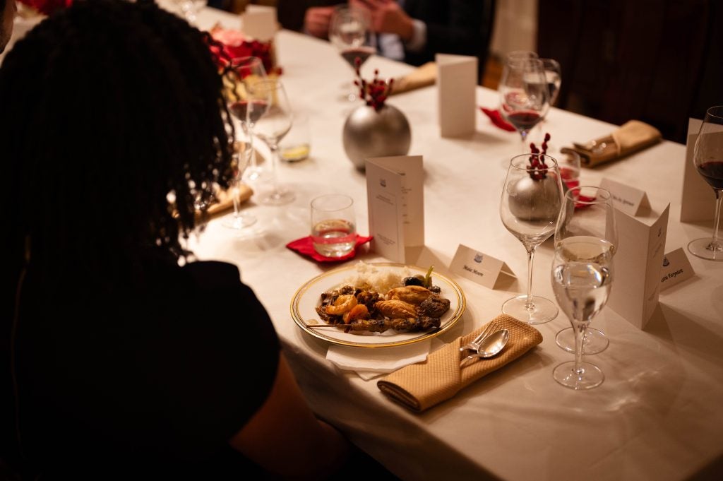 A plate of food on a table with white tablecloth and a formal setting