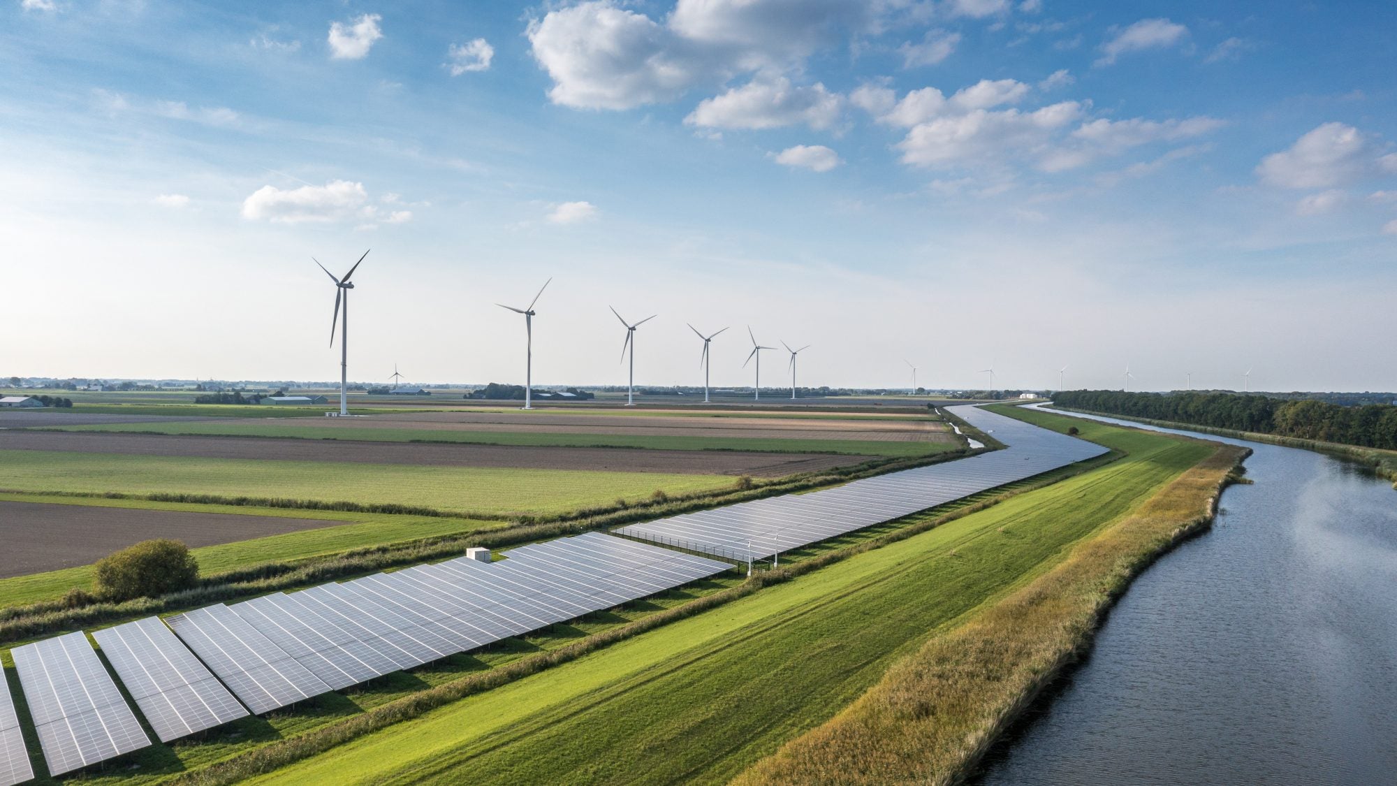 Solar panels and windmills on a green field on a sunny day