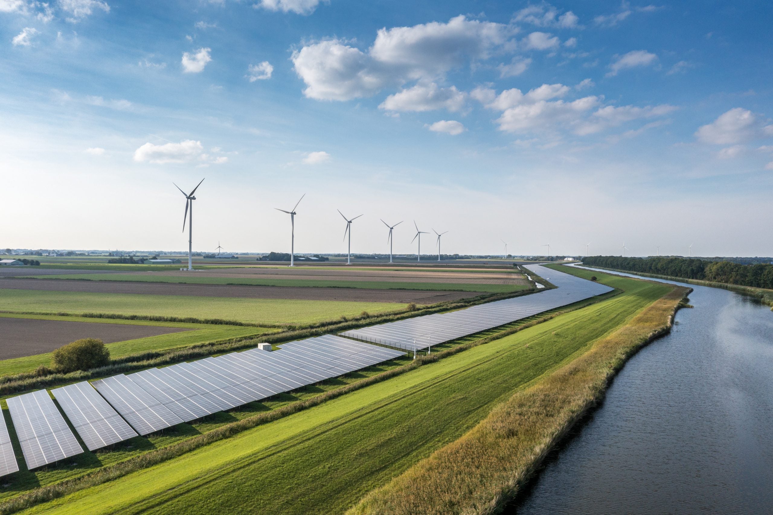 Solar panels and windmills on a green field on a sunny day