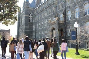 Students walk past a stone building on Georgetown's campus on a spring day.