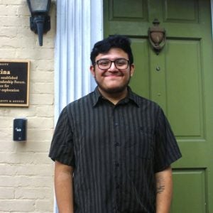 A senior at Georgetown stands in front of a green door of a house near Georgetown's campus.