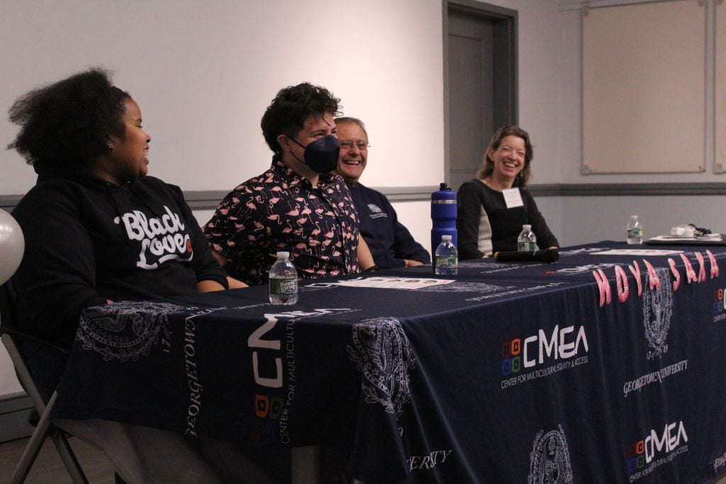 A group of faculty panelists sit behind a desk and talk to students.