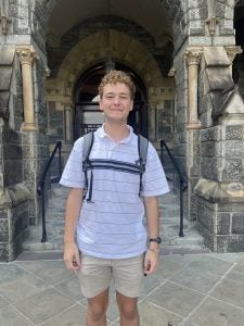 Young man in a polo shirt with a backpack on in front of Healy Hall.