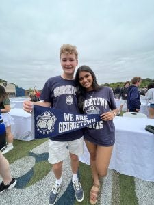 A young man and woman in Georgetown gear on a cloudy day holding a GU flag