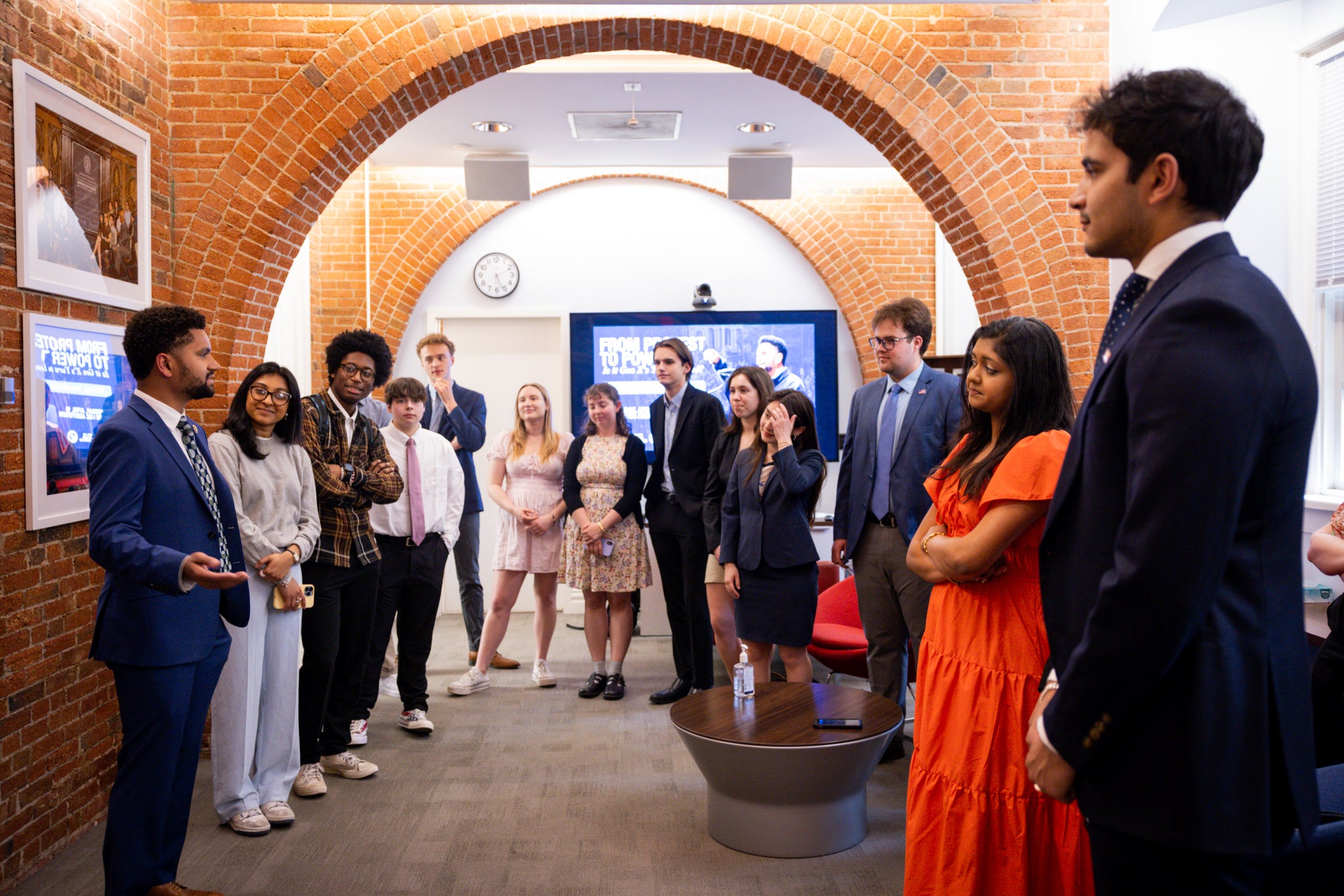 A group of students stand under an arch inside a building.