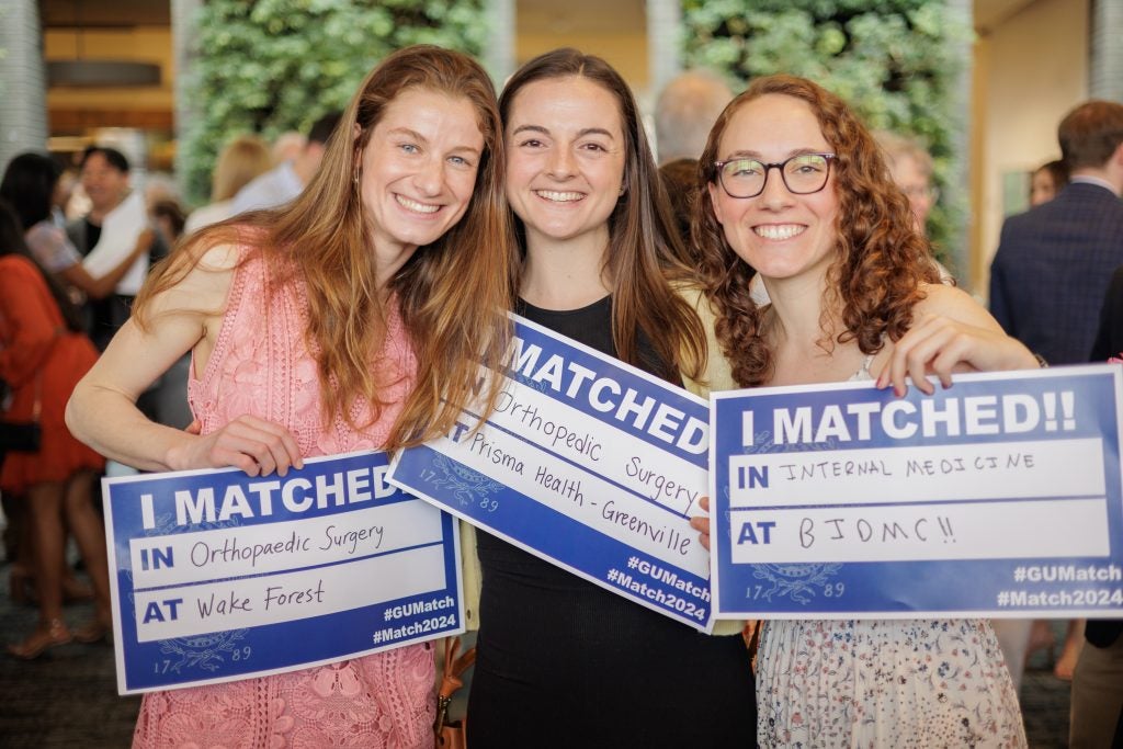 Three young women on match day with match day signs