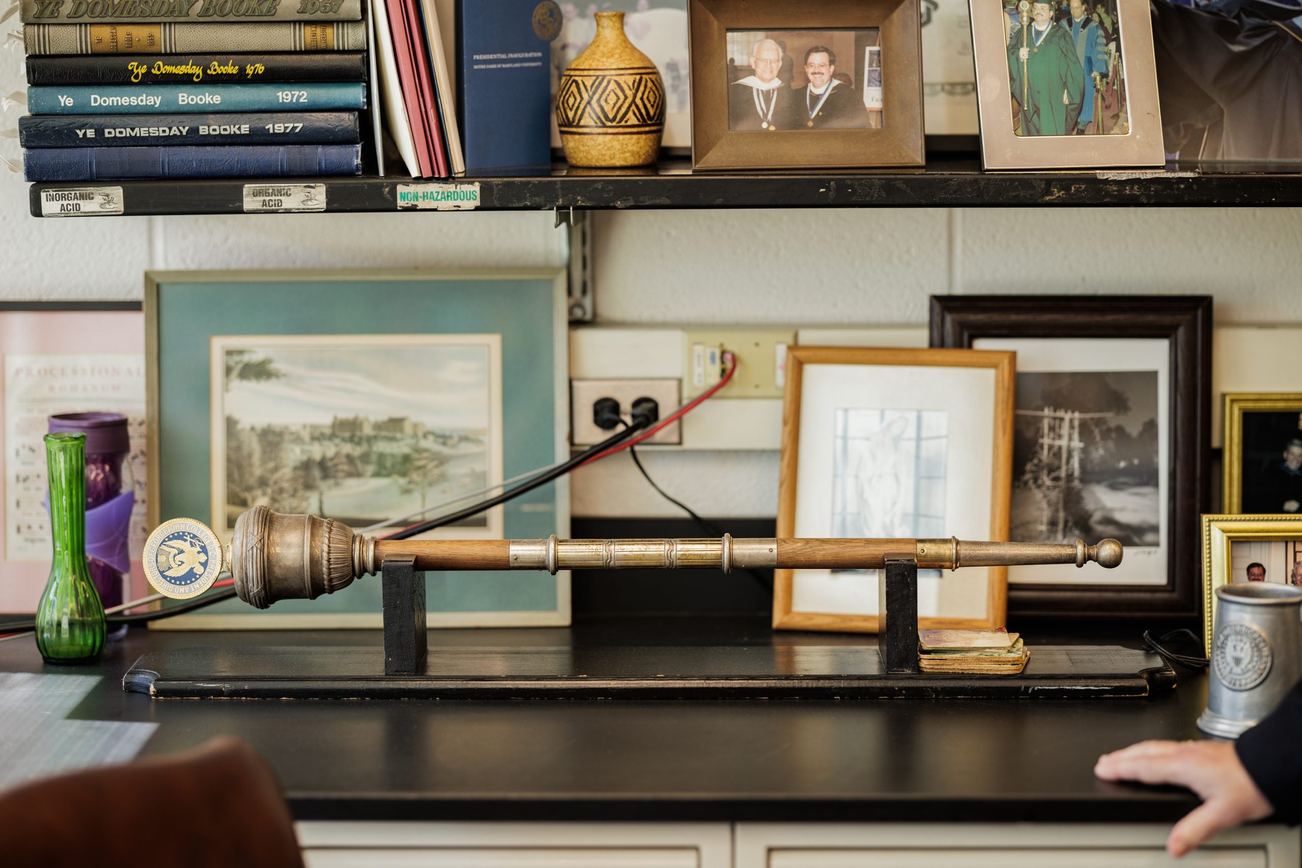 A mace, or heavy staff emblazoned with a seal at the top, sits in a holder in an office.
