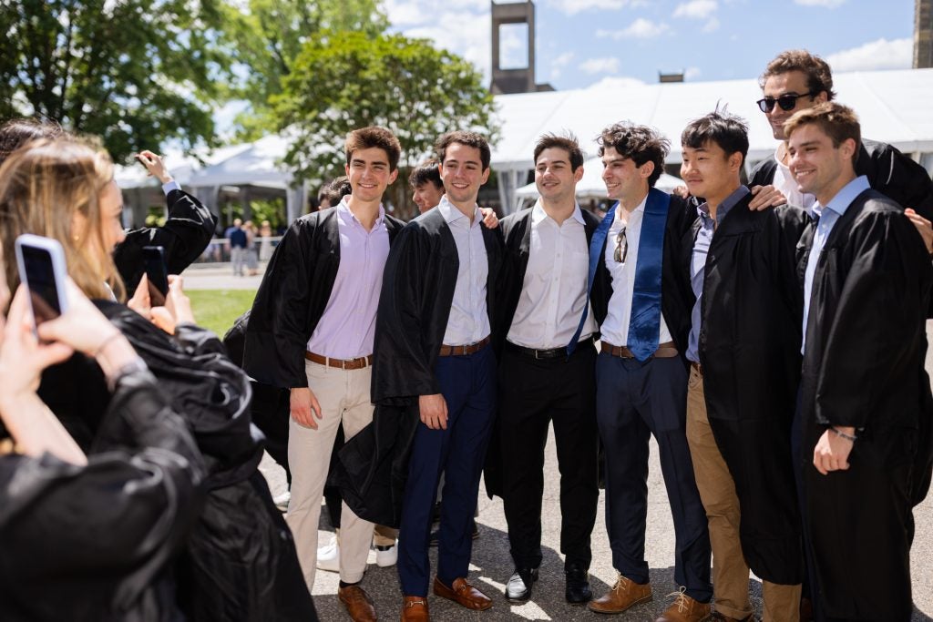 A group of seven Georgetown graduates in graduation gowns pose for a photo together in Healy Circle