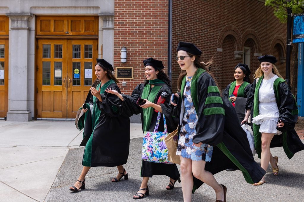 A group of Georgetown School of Medicine graduates walk in their caps and gowns across campus