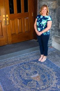 A white woman stands next to Georgetown's blue seal outside a building.