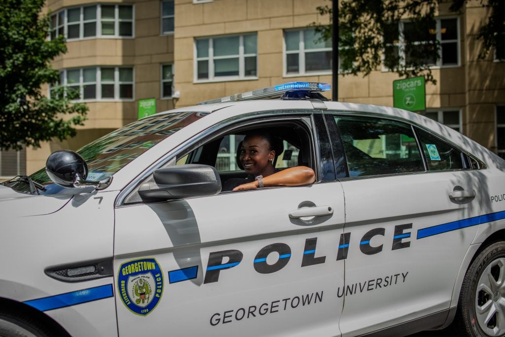 A police officer smiles out the window of her police car.