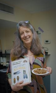 Martha Weiss holding a plate of cicadas and her book on cicadas