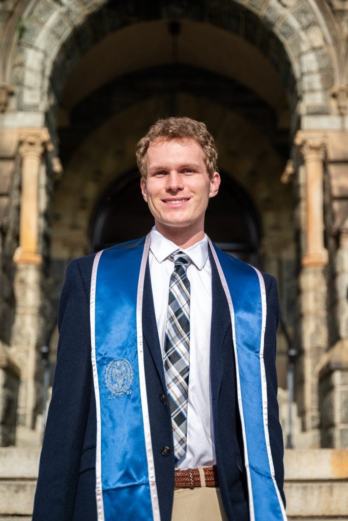 Eddie Hoffman (CAS’24) posing for his graduation photo in front of Healy Hall.