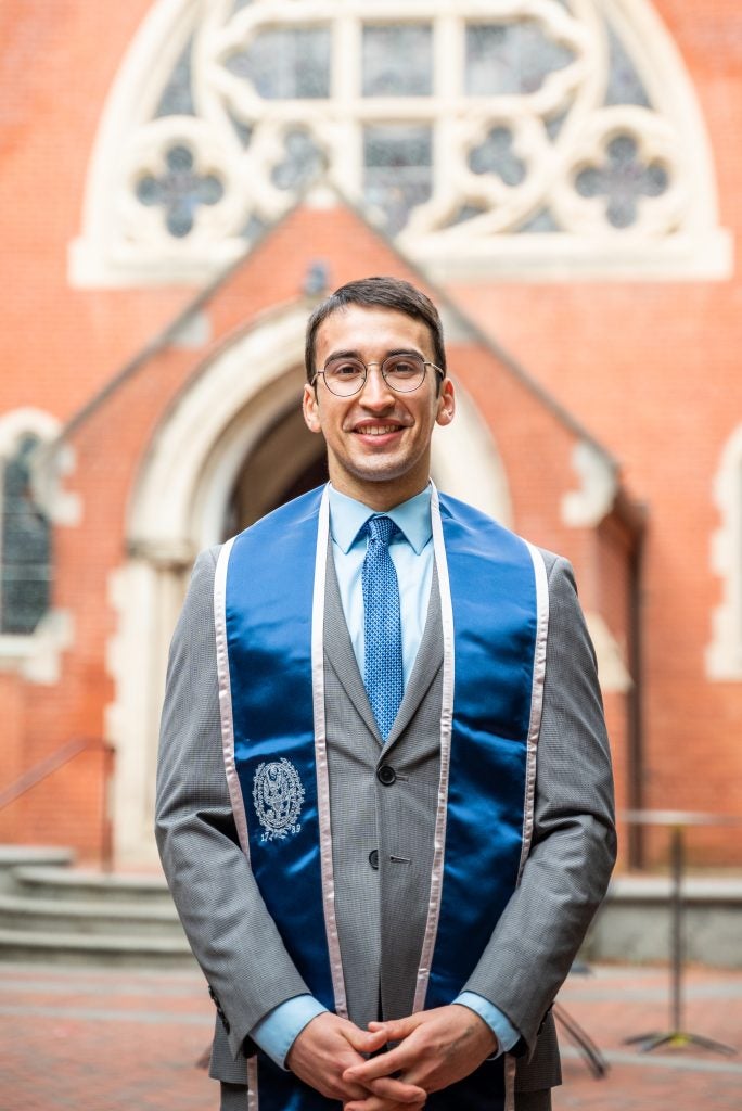 Joseph Herlihy (SFS’24, G‘25) posing for his graduation photo in Dahlgren Quad.