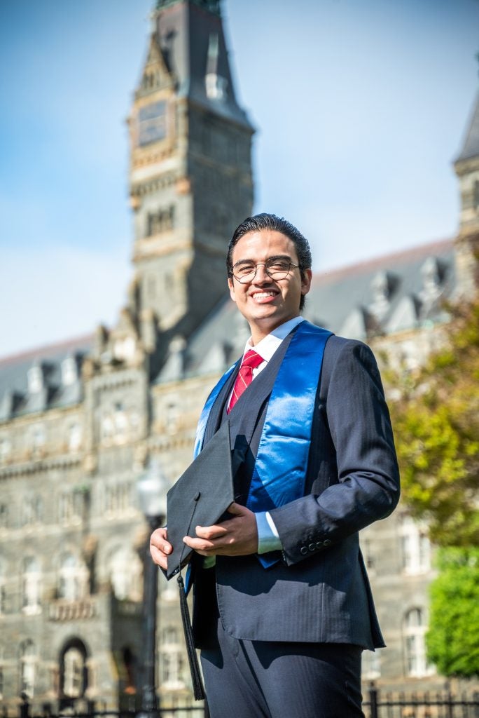 Renato Llontop Calosi (SFS’24) posing for his graduation photo in front of Healy Hall. 