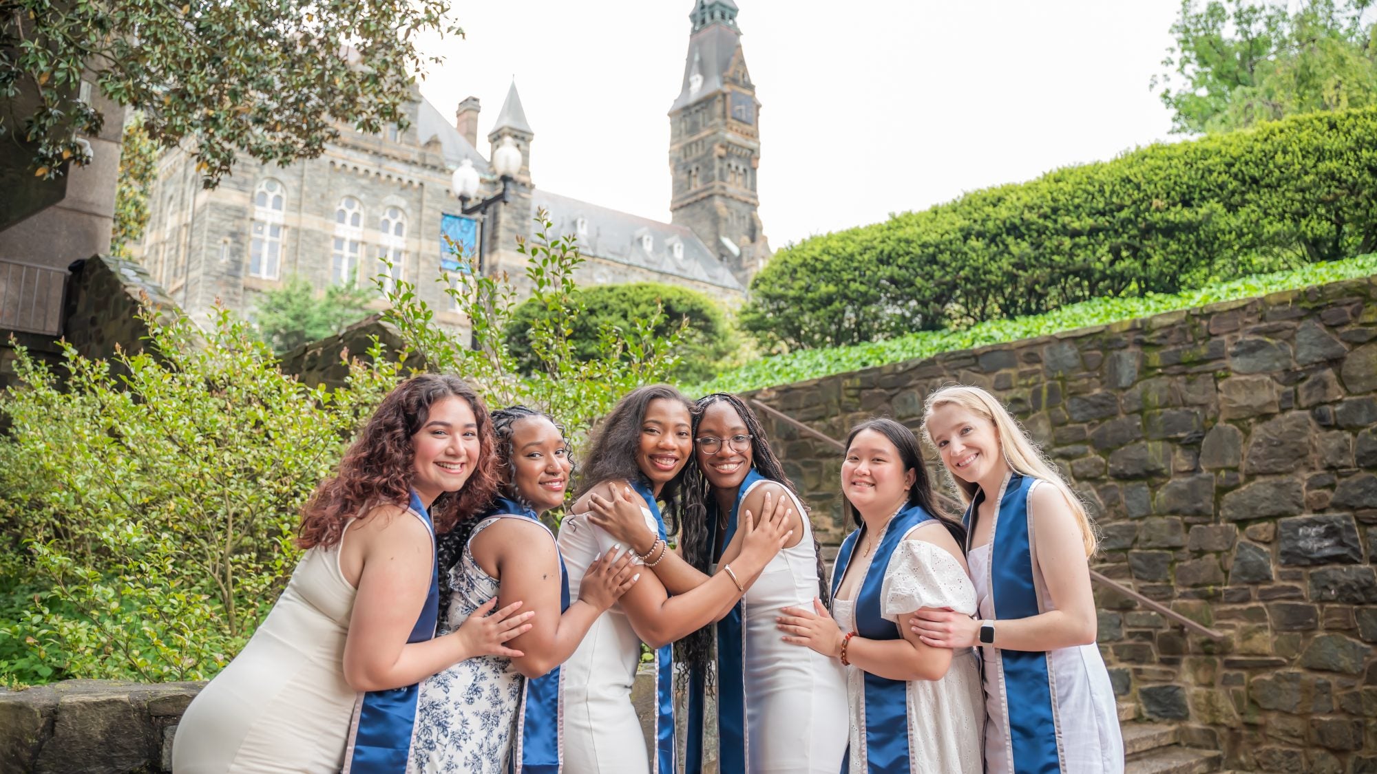 A group of six GU graduates posing for grad photos on the Lauinger Steps on an overcast day