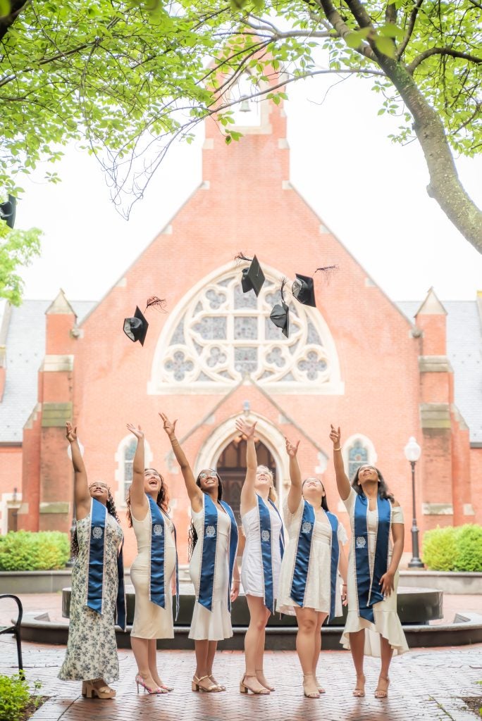 Christine Mauvais (N’24) and her friends tossing their graduation caps in Dahlgren Quad.