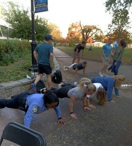 A police officer does push-ups with students.