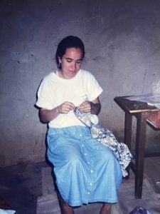 Lahra Smith sewing in a dimly lit room in Zimbabwe