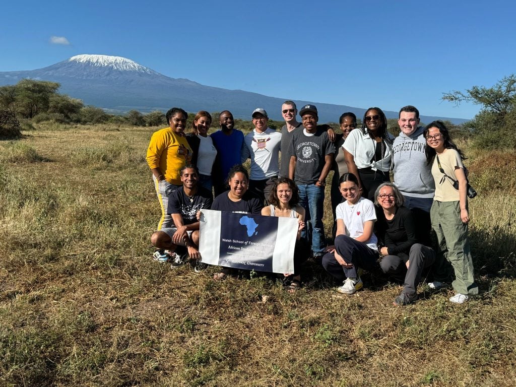 Lahra Smith and her students in field in Kenya with a mountain in the background.