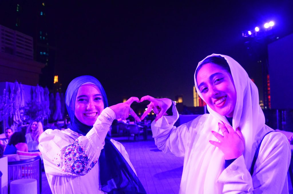 Two young women at the Senior Dinner in dim purple light in a ballroom setting.