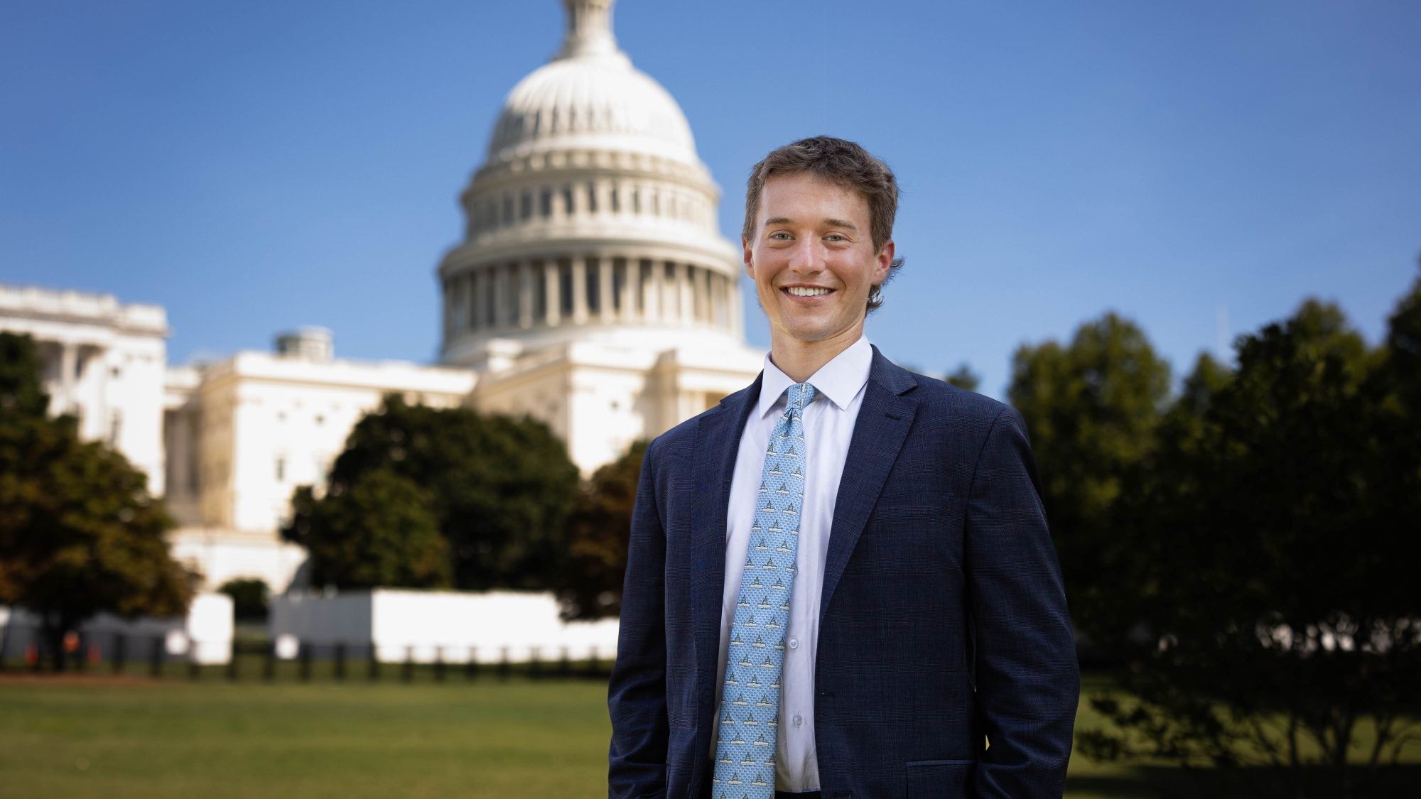 Luke Hughes in a suit and tie by the US Capitol on a clear day