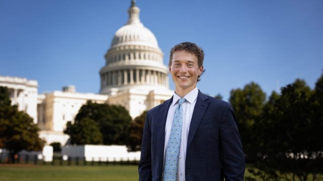 Luke Hughes in a suit and tie by the US Capitol on a clear day