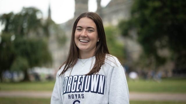 Sarah Brannigan wearing a light grey GU sweatshirt on Healy Lawn