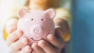 Two hands holding a pink piggy bank