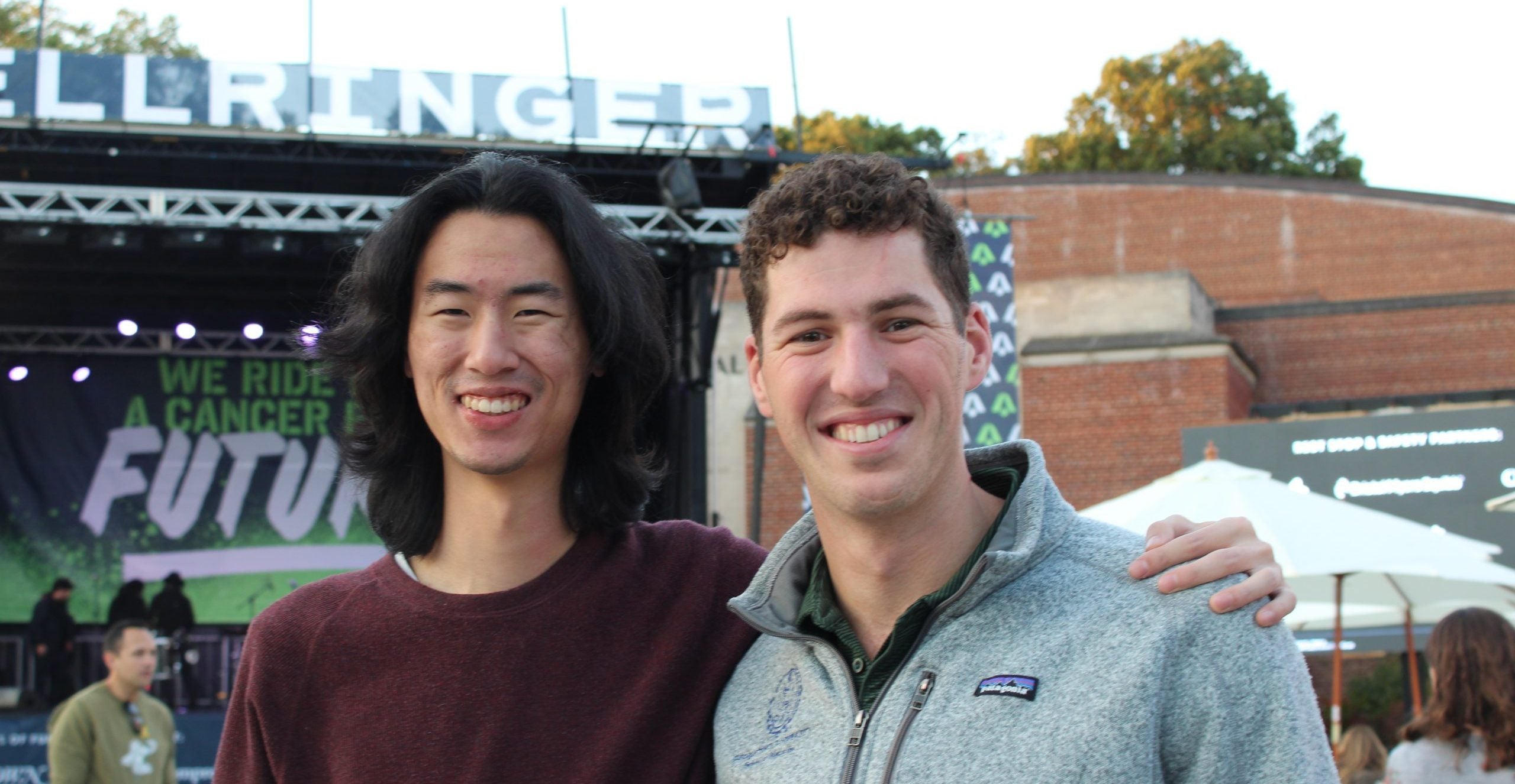 Two men pose in front of a banner that says BellRinger.
