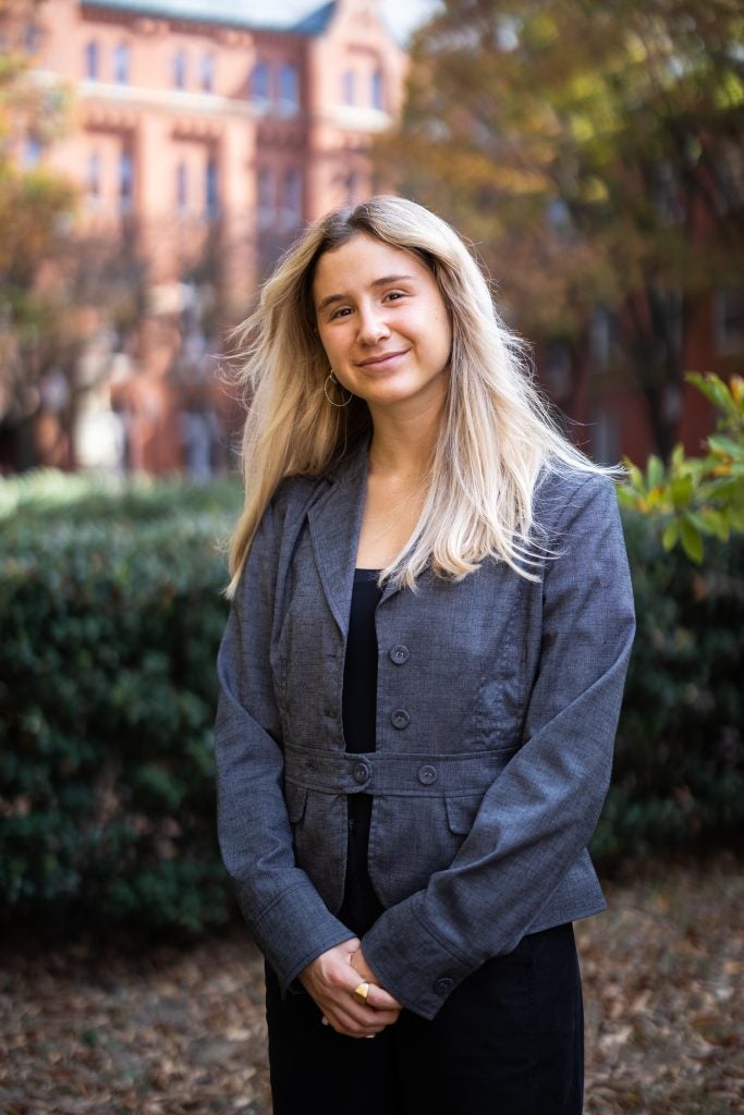 Noa Offman, a 2025 Rhodes winner, stands with her hands crossed in front of her on Georgetown's campus.