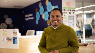 Lionell Daggs in the OSEI building sitting at a table looking at the camera