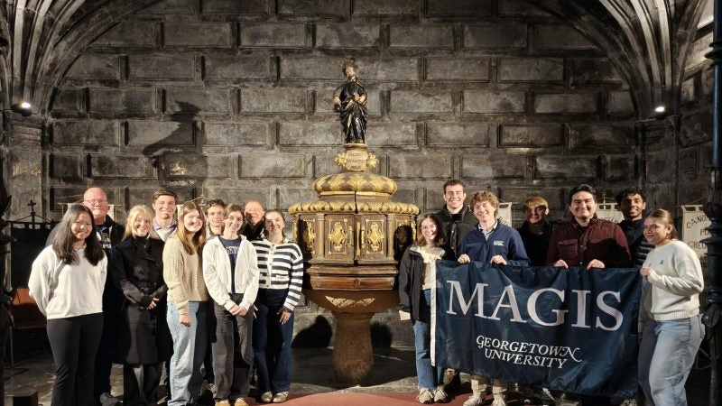 Students standing in a church while holding a Georgetown flag