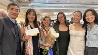 A family poses with a medical student on Match Day. She holds an envelope in her hand.