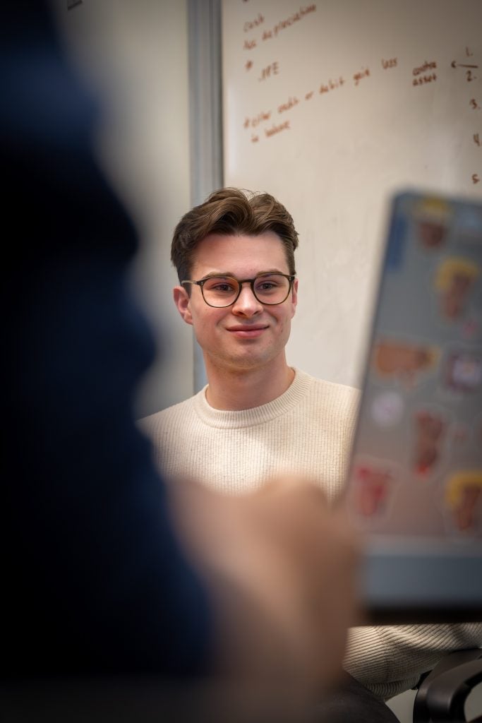 Student smiles as he watches another student's presentation