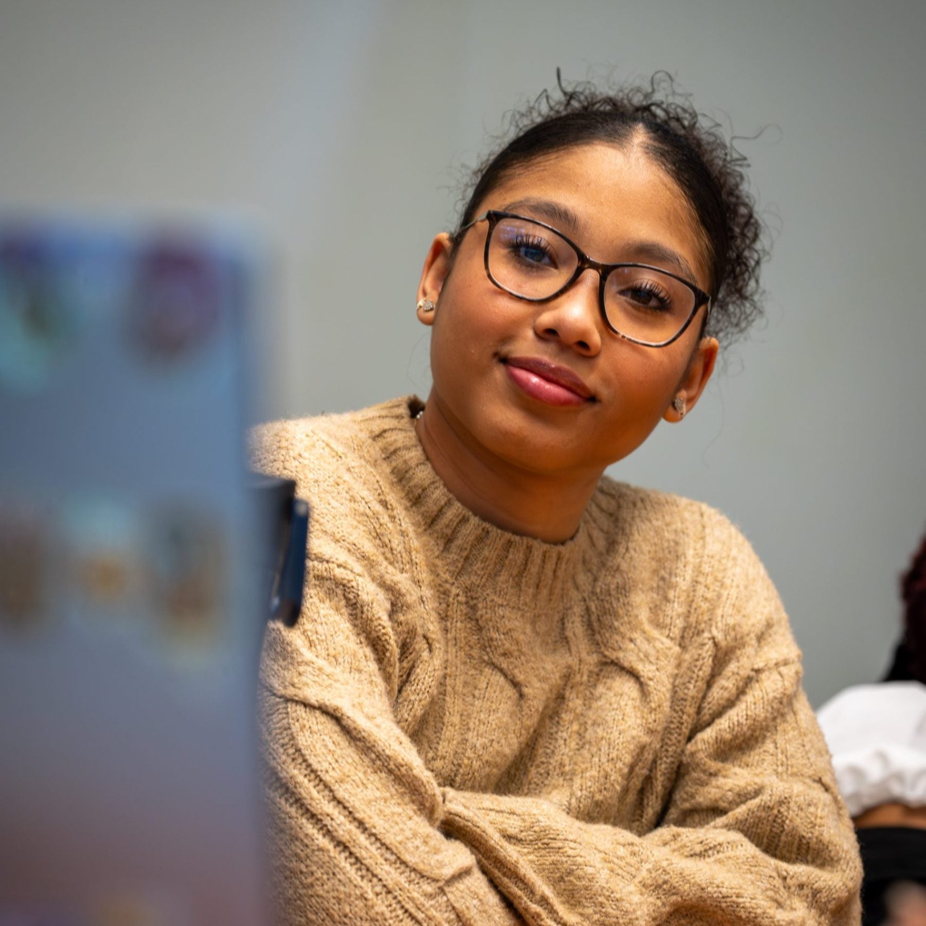 Student smiles as another student gives a presentation